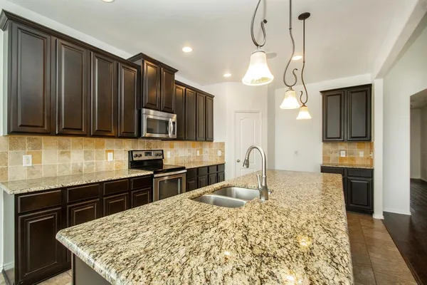 a kitchen with stainless steel appliances kitchen island granite countertop a stove sink and cabinets