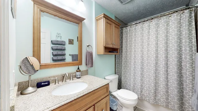 a bathroom with a granite countertop sink mirror vanity and toilet