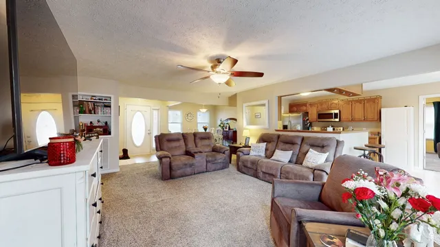 a living room with furniture kitchen view and a chandelier