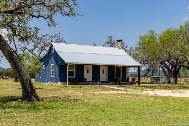a view of a white house with a large tree