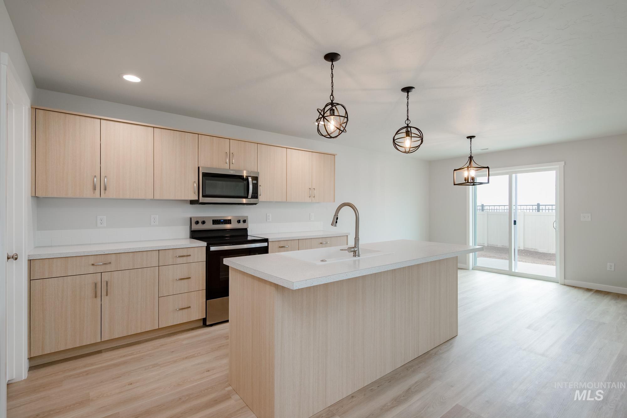 2391 West Fallon Loop Nampa, ID 83651 - Photo 3 of 20 Contemporary kitchen featuring light wood-finish cabinetry, white countertops, stainless steel appliances, a center island with sink, and light wood-finish flooring