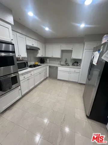 a kitchen with stainless steel appliances a stove a sink a microwave a refrigerator and cabinets