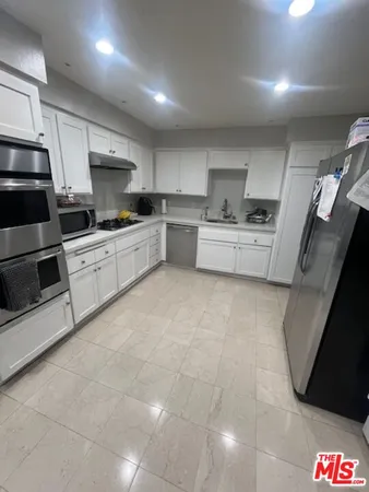 a kitchen with stainless steel appliances a stove a sink a microwave a refrigerator and cabinets