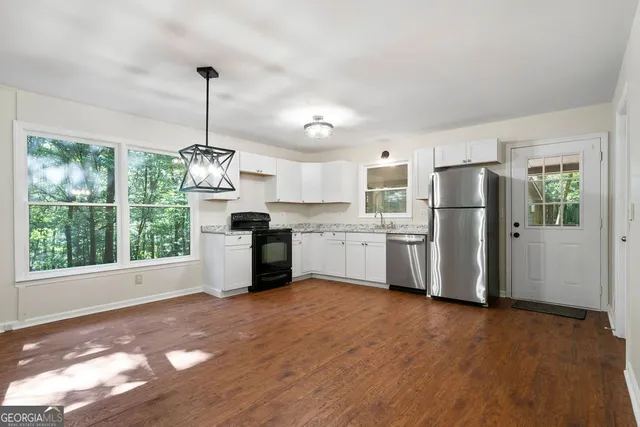 a kitchen with stainless steel appliances granite countertop a refrigerator a sink dishwasher a stove and white cabinets with wooden floor