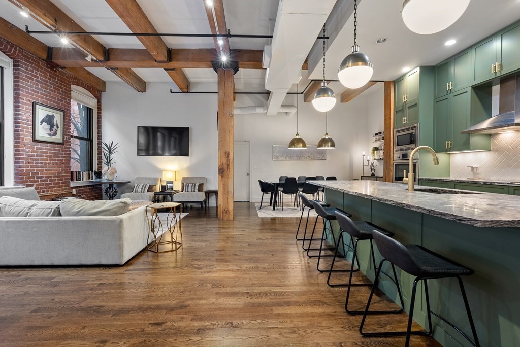 15 Sleeper Street, Unit 302 Boston, MA 02210 - Photo 2 of 35 a living room with couches a coffee table and kitchen view with wooden floor