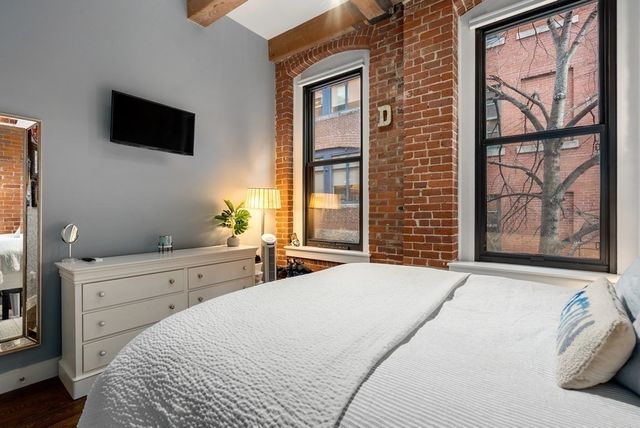 a bedroom with a bed and a flat tv screen on dresser