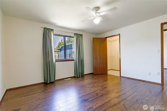 an empty room with wooden floor and a ceiling fan