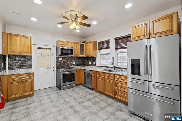 a kitchen with stainless steel appliances granite countertop a refrigerator stove top oven and sink