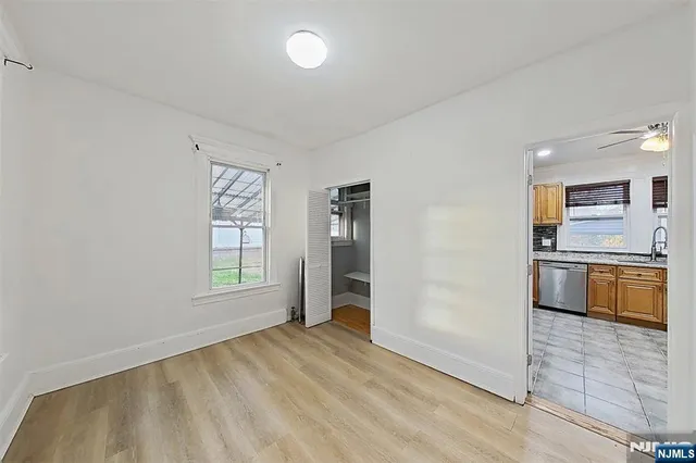 an empty room with windows and kitchen view