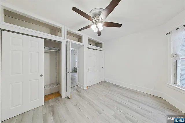 an empty room with wooden floor fan and windows