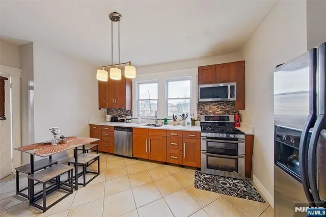 a kitchen with stainless steel appliances granite countertop a stove top oven a sink a dining table and chairs