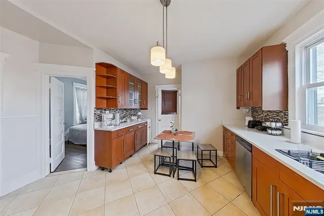 a large kitchen with a stove a sink dishwasher a dining table and chairs with wooden floor