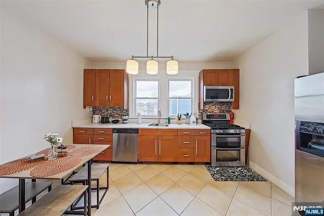 a kitchen with stainless steel appliances granite countertop a stove a sink dishwasher a refrigerator and a dining table with the kitchen view