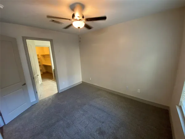 an empty room with a chandelier fan and a window