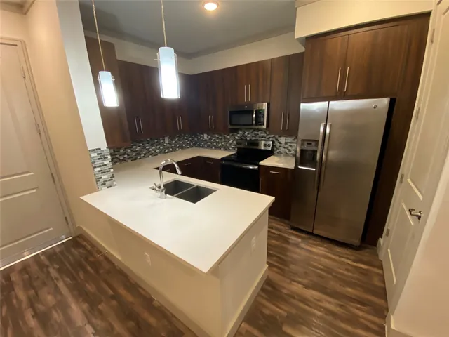 a kitchen with stainless steel appliances a refrigerator a sink a stove a microwave a counter top and cabinets