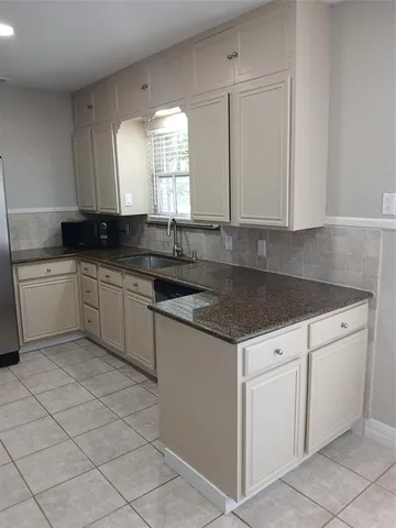 a kitchen with white cabinets sink and window