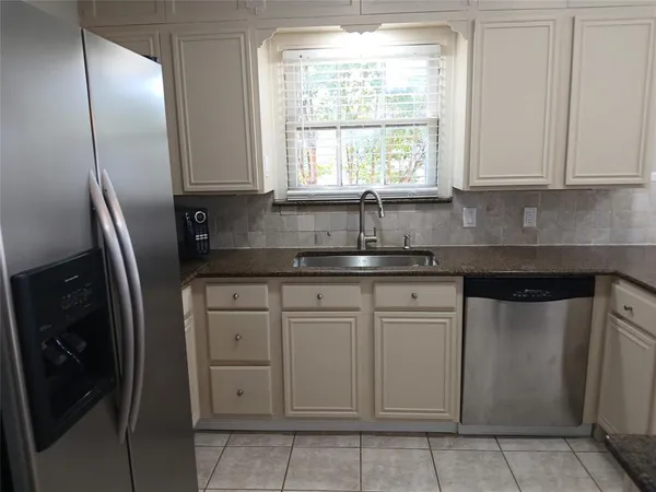 a kitchen with stainless steel appliances granite countertop white cabinets sink and window