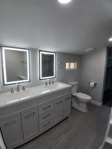 a bathroom with a toilet sink double vanity and mirror