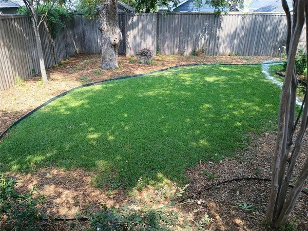 a backyard of a house with lots of green space and wooden fence