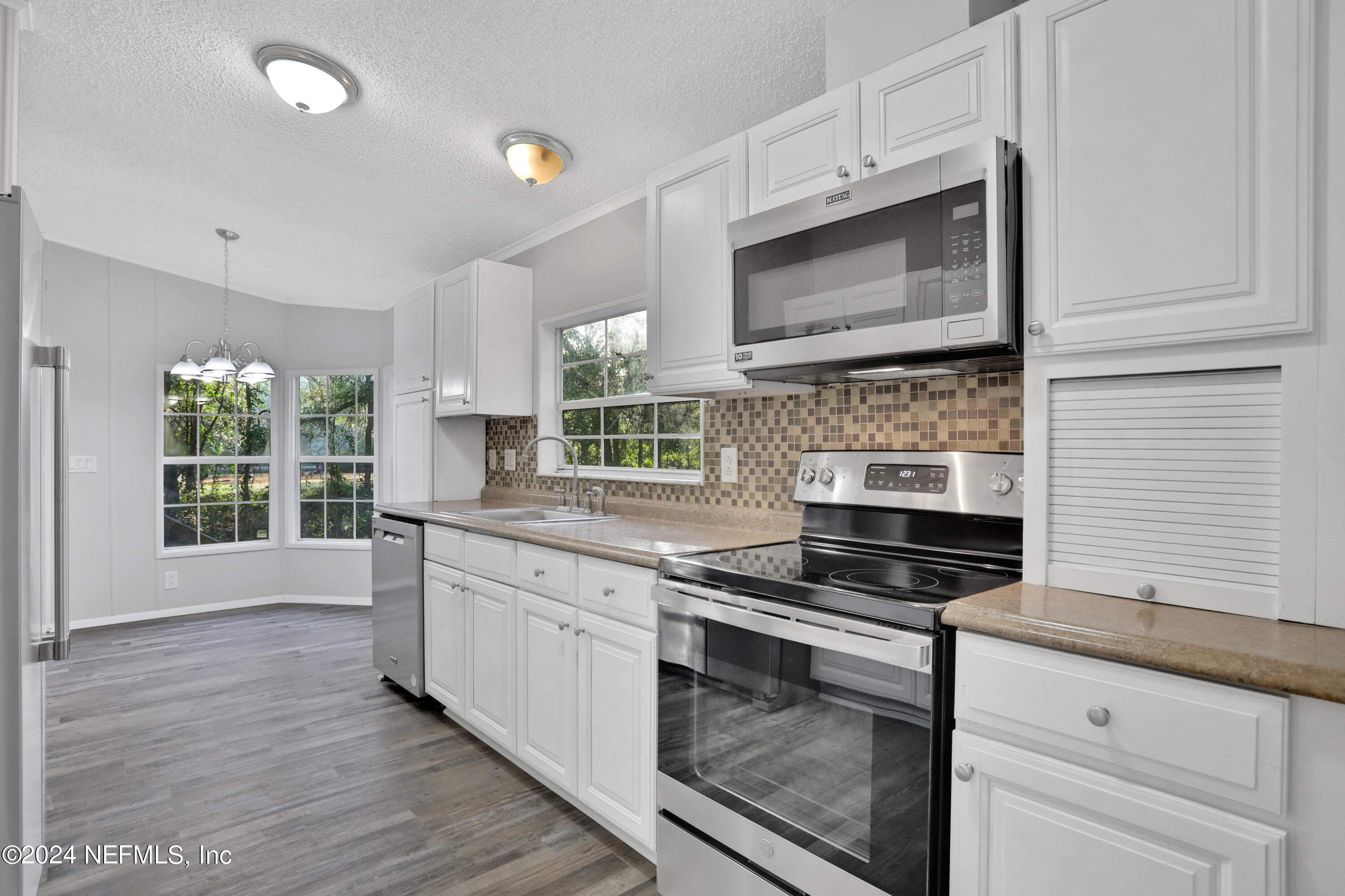 54337 Pelican Road Callahan, FL 32011 - Photo 8 of 32 a kitchen with stainless steel appliances kitchen island granite countertop a stove and a microwave