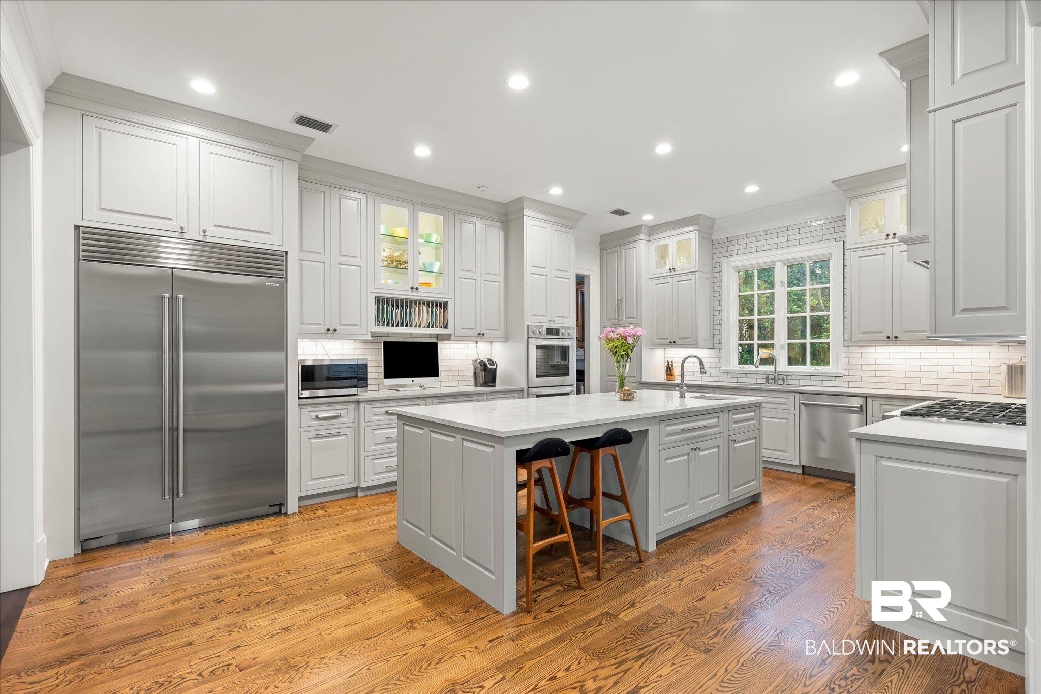 4008 McGregor Oaks Mobile, AL 36608 - Photo 11 of 50 Kitchen featuring appliances with stainless steel finishes, an island with sink, backsplash, light wood finished floors, and recessed lighting