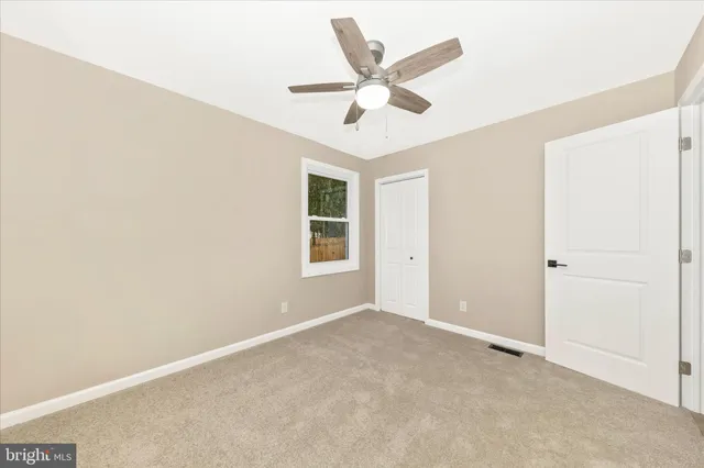 an empty room with ceiling fan and window