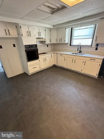 a kitchen with cabinets a sink and white appliances