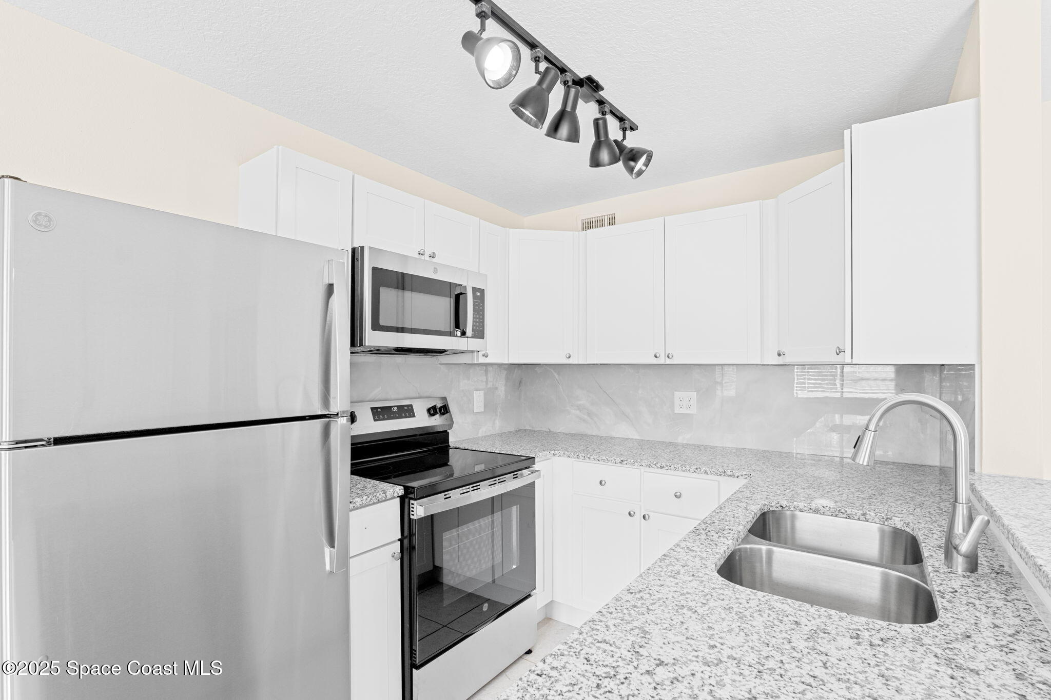 1884 Agora Circle Southeast, Unit 101 Palm Bay, FL 32909 - Photo 9 of 18 a kitchen with stainless steel appliances granite countertop a sink stove and refrigerator