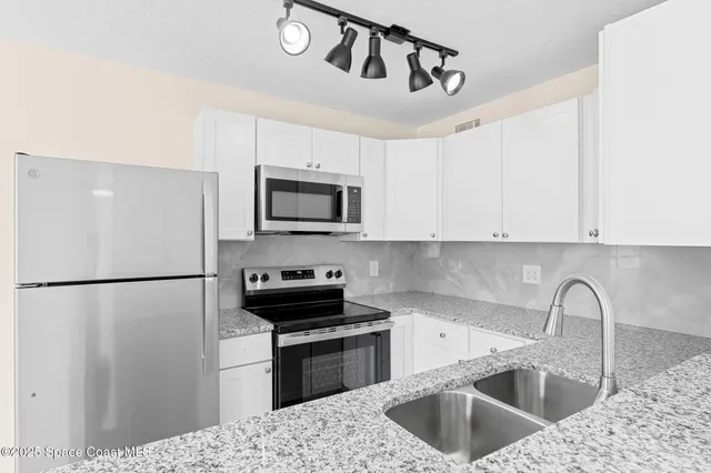 a kitchen with a refrigerator sink and white cabinets