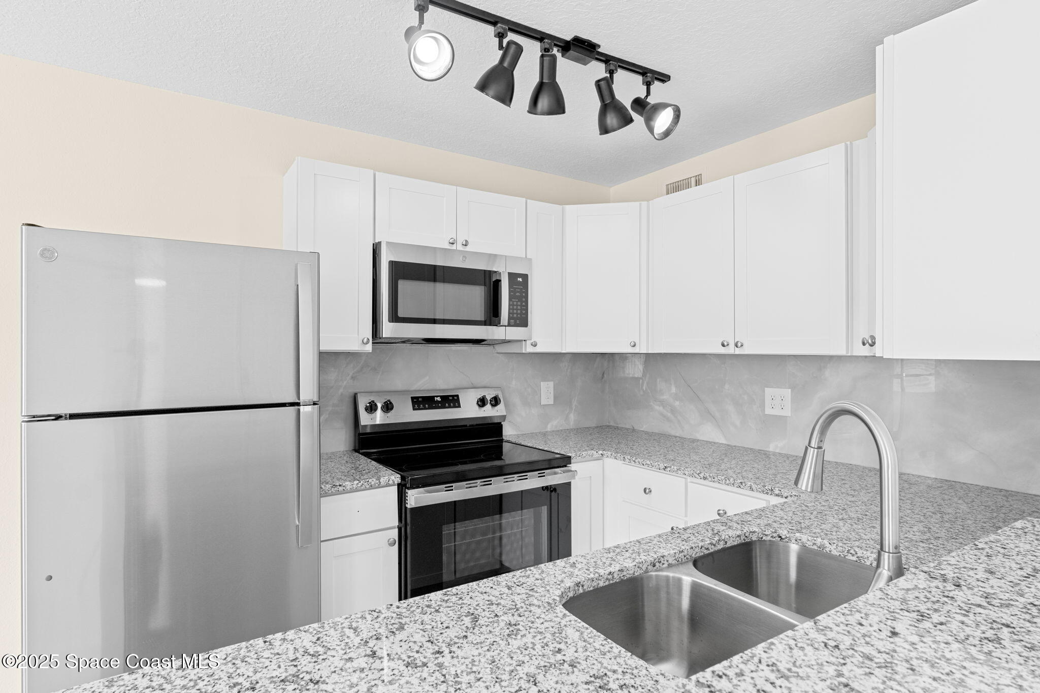 1884 Agora Circle Southeast, Unit 101 Palm Bay, FL 32909 - Photo 10 of 18 a kitchen with a refrigerator sink and white cabinets