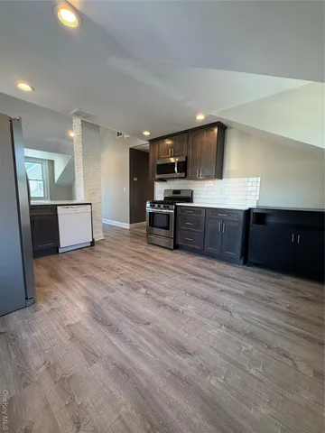 a large kitchen with a wooden floor and stainless steel appliances