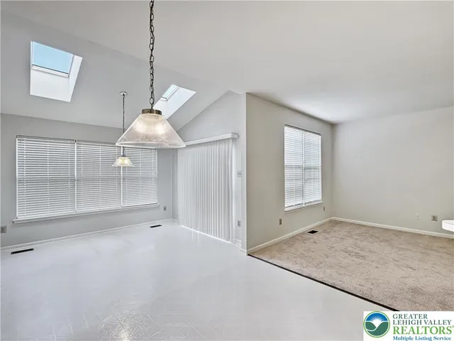 an empty room with windows and chandelier fan