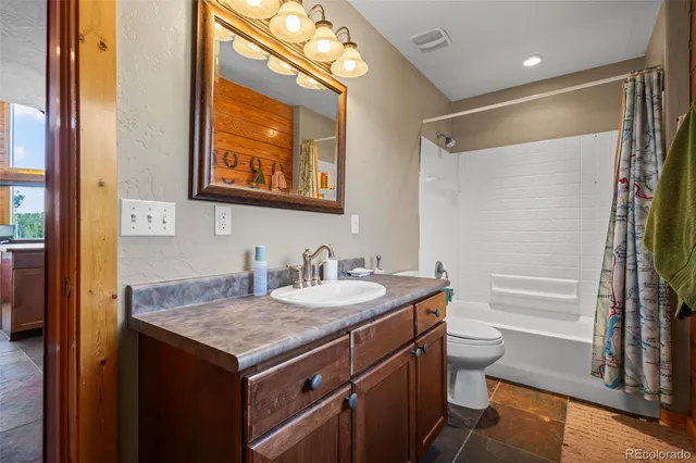 a bathroom with a granite countertop sink mirror vanity and toilet