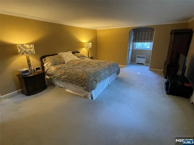 a spacious bedroom with a bed and a flat tv screen on the dresser