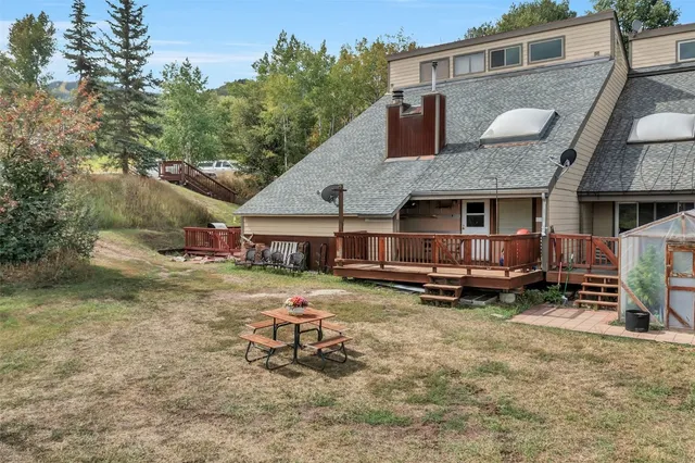 a view of a backyard with large trees and wooden fence