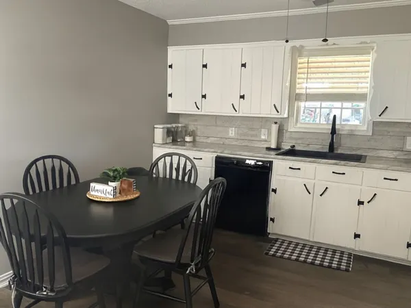 a kitchen with granite countertop a dining table chairs and white cabinets