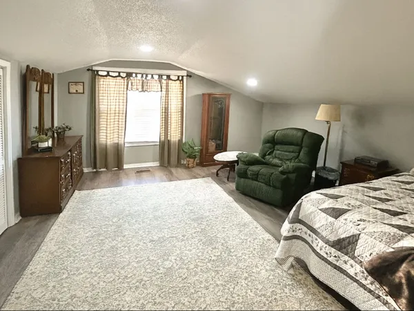 a spacious bedroom with a bed a couch and large windows