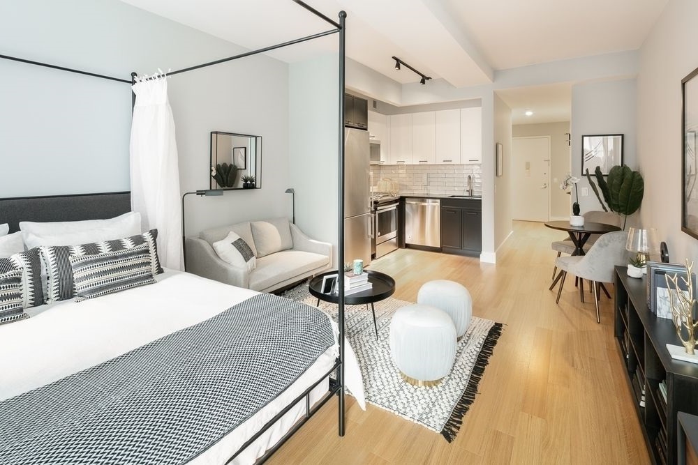 63 Wall Street, Unit 405 Manhattan, NY 10005 - Photo 5 of 20 a bedroom with a bed mirror and window