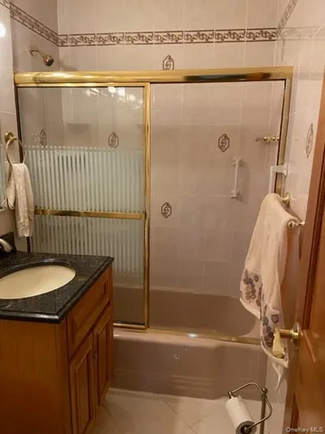 a bathroom with a granite countertop bathtub shower sink vanity and toilet