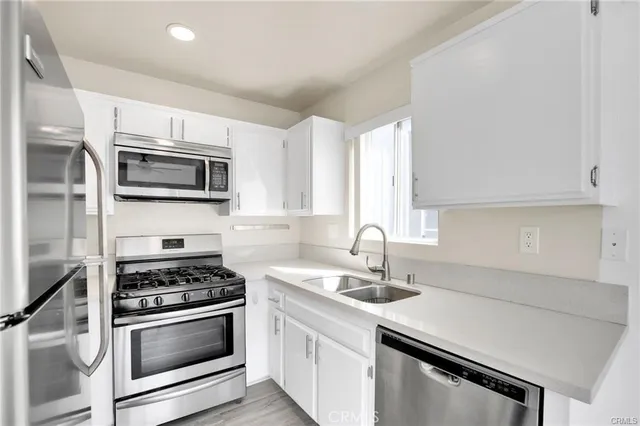 a kitchen with granite countertop a sink dishwasher stove and microwave with wooden floor