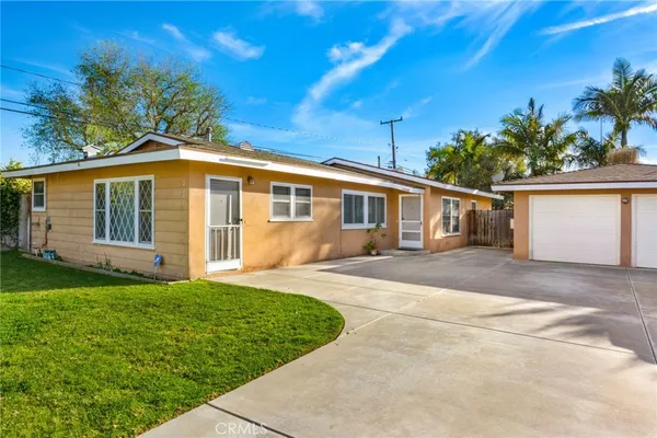a view of a yard in front of a house with plants and large tree