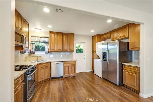 a kitchen with stainless steel appliances granite countertop a refrigerator a stove top oven and sink
