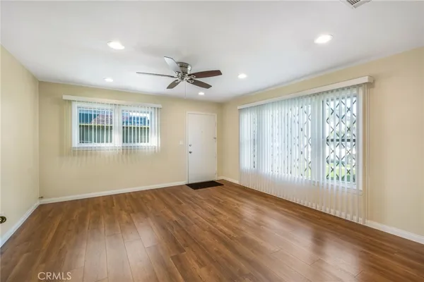 an empty room with wooden floor and windows