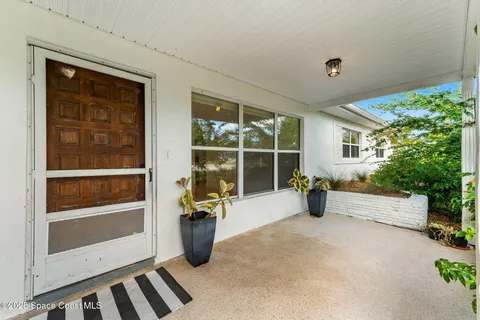 a view of an empty room with a window and potted plants