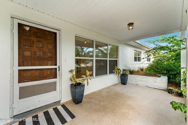 a view of an empty room with a window and potted plants
