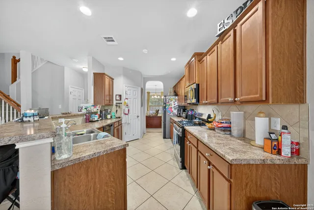 a kitchen with stainless steel appliances granite countertop a sink stove refrigerator and cabinets
