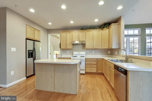 a kitchen with kitchen island granite countertop a sink appliances cabinets and furniture