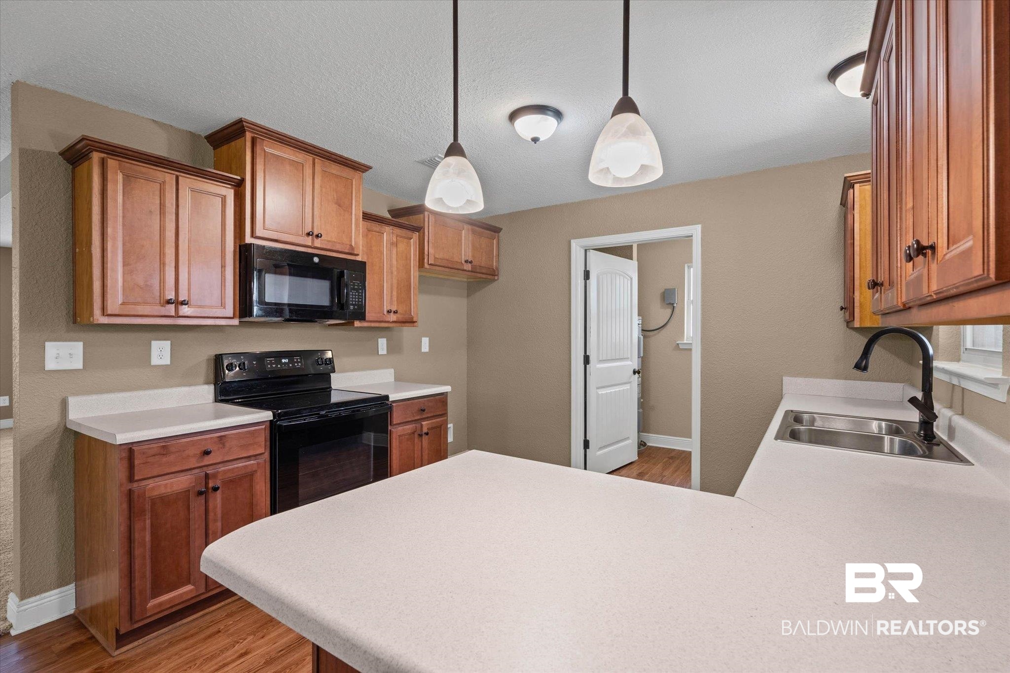 101 Washington Boulevard Foley, AL 36535 - Photo 11 of 32 Kitchen featuring black appliances, wood finish cabinets, light countertops, light wood-style floors, and decorative light fixtures