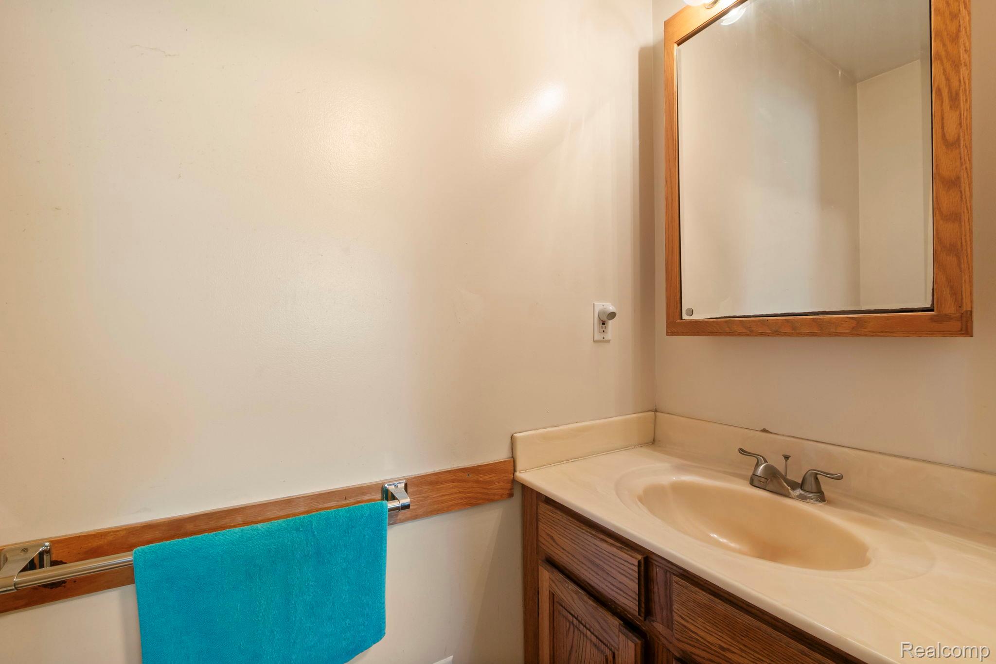 76565 McFadden Road Armada, MI 48005 - Photo 41 of 95 Integrated vanity with an oval basin, wood-finish cabinetry, chrome faucet, and overhead wood-framed mirror