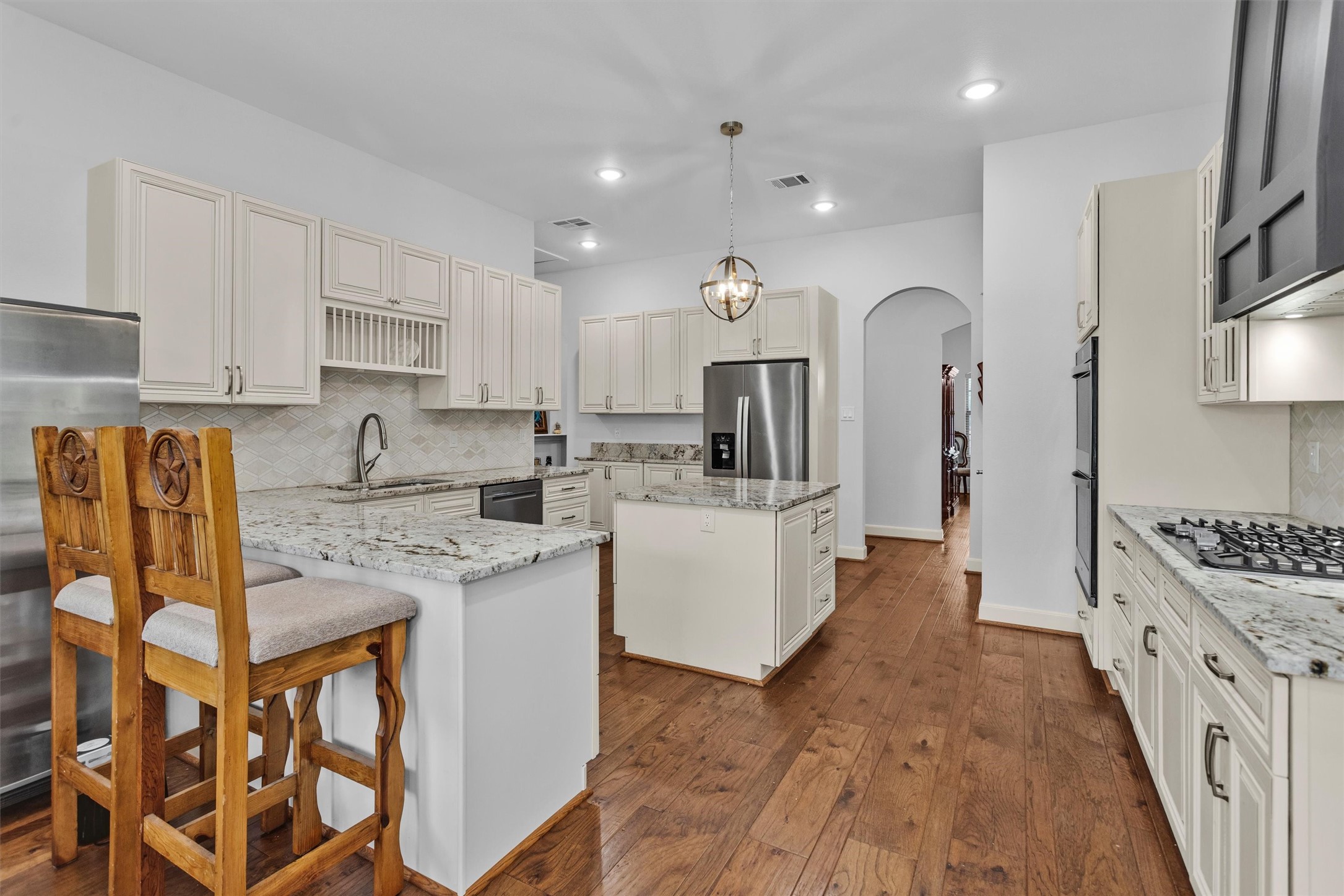264 Grey Feather Road Huntsville, TX 77340 - Photo 10 of 31 a kitchen with stainless steel appliances granite countertop a stove top oven a sink a refrigerator white cabinets and couches with wooden floor